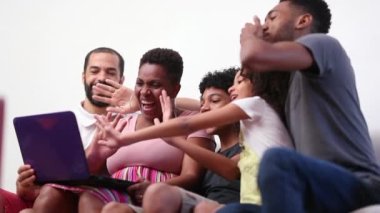 Lovely family waving hello to laptop webcam, parents and children talking with relatives