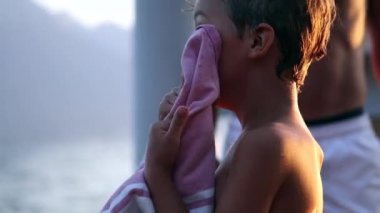 Child holding towel drying body