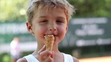 Kid eats ice-cream. Young boy child eating icecream dessert