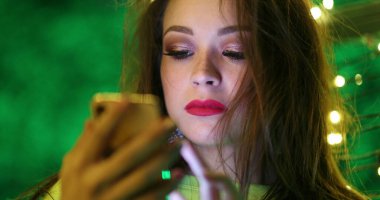 Gece akıllı telefon kullanan güzel kız cep telefonu ekranına dokunuyor.