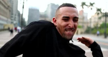 Happy hispanic man receiving good news dancing in street feeling joy