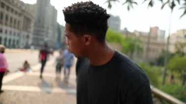 Young black man shaking head in downtown street dancing to beat song