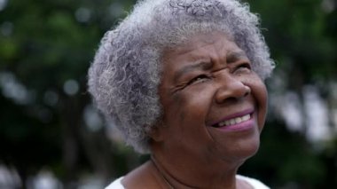 A contemplative senior woman standing outside looking to sky with HOPE and FAITH