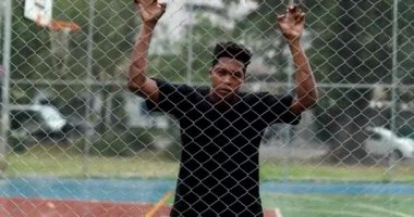 Upset African man leaning on metal fence. Angry black person shaking fence