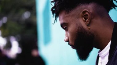 Düşüncelere dalmış meditasyoncu bir Afrikalı sokakta duvara yaslanıyor.