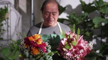 One Happy Asian Florist professional holding two bouquet of flowers for client. Portrait of middle age entrepreneur of small business