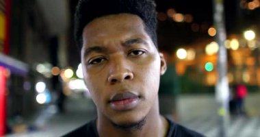 African male standing outside in city looking at camera with serious face