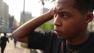 Contemplative young black man thinking outside. African person standing downtown city