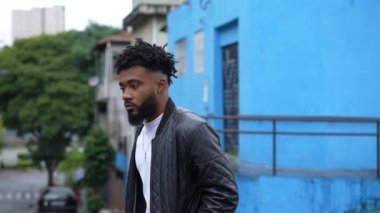 A pensive young black man walking outside in urban street a thoughtful African person