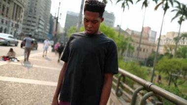 Young black man shaking head in downtown street dancing to beat song
