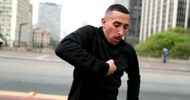 Happy hispanic man dancing in downtown city in street