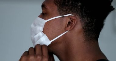 Profile African man putting surgical face mask