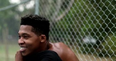 African man putting t-shirt on outside and wiping sweat after sport