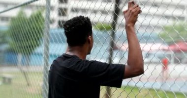 Pensive young black man leaning on metal fence. Contemplative mixed race person