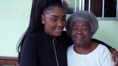 Büyükannesini kucaklayan genç bir torun siyah bir kız büyük anne ve babasını kucaklıyor.
