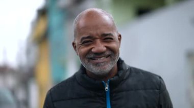 Mutlu bir son sınıf zenci portresi. Kameraya gülümsüyor. Sokakta dikiliyor.