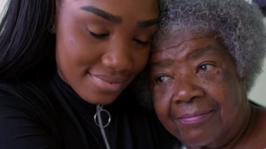A teen granddaughter embracing senioro grandmother showing love kissing grandparent on forehead