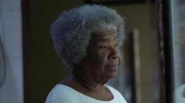 Düşünceli bir Afrikalı son sınıf öğrencisi. Pencerenin önünde dikiliyor. Düşünceli bir siyahi 80 'li yaşlarda.