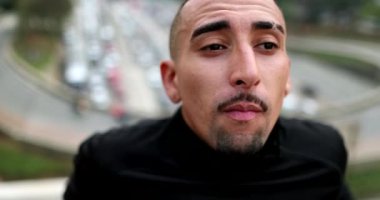 Thoughtful hispanic man in downtown city thinking, real people