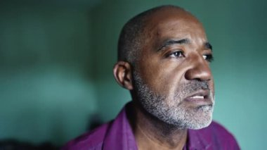 A thoughtful older senior man An African person pondering decision staring out window