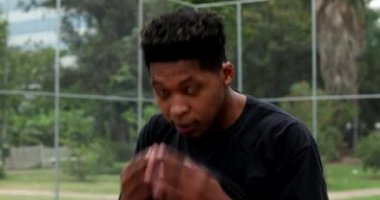 Black man feeling heat wiping forehead sweat with t-shirt