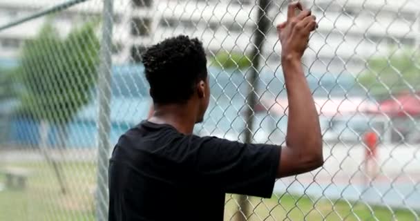 Ευσεβής Νεαρός Μαύρος Που Στηρίζεται Μεταλλικό Φράχτη Προκλητικό Άτομο Μικτής — Αρχείο Βίντεο