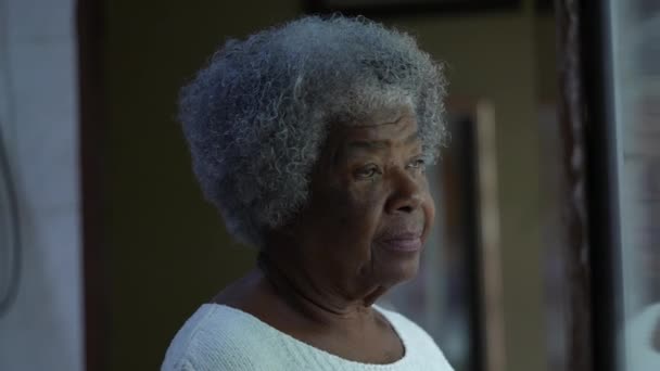 一位心事重重的非洲老年妇女站在窗边 她是一位80多岁的有思想的黑人 — 图库视频影像