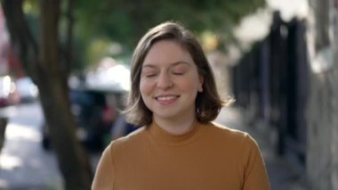 Portrait of a happy young woman walking in city sidewalk. Millennial girl in 20s walks forward feeling confidence