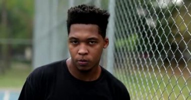 Serious black African man looking at camera walking backwards