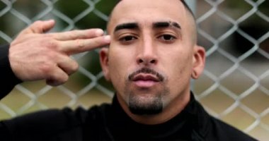 Hispanic man pulling trigger. pointing at head with pretend gun, headshot with finger