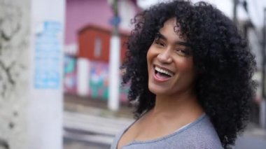 A happy confident young black woman smiling and laughing standing in street