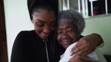 Büyükannesini kucaklayan genç bir torun siyah bir kız büyük anne ve babasını kucaklıyor.