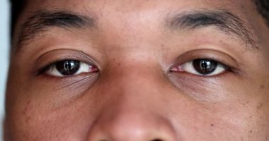 Close-up young black man eyes looking at camera, macro african person face