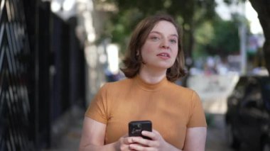 Young woman checking for directions map on cellphone app. Person searching for place on phone looking at cellphone screen while walking in city street