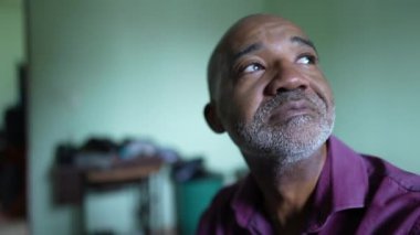 Umut dolu, siyahi, kıdemli bir adam pencereden dışarı bakıyor.