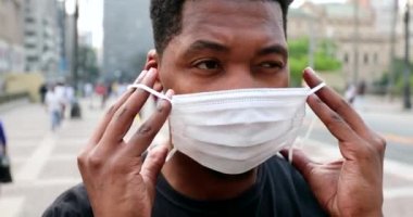Young black african american putting covid-19 face mask in urban downtown city