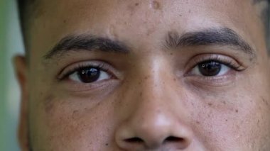 A hispanic man becoming serious close-up face and eyes looking at camera