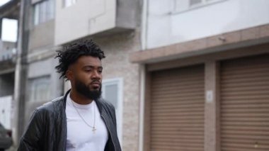 A thoughtful African guy walking in slow-motion in street