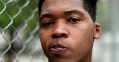 Thoughtful young black man standing outside thinking. Pensive mixed race person