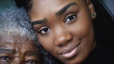 Nesil kadın portresi, kameraya birlikte poz veren bir büyükanne ve toruna bakıyor.