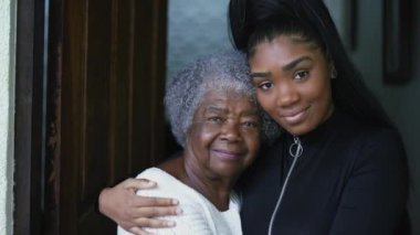 A teen granddaughter embracing senioro grandmother showing love kissing grandparent on forehead