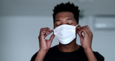 African person taking off surgical face mask feeling relief and smiling