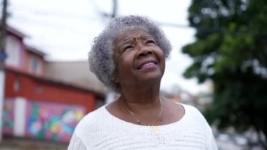A contemplative senior woman standing outside looking to sky with HOPE and FAITH