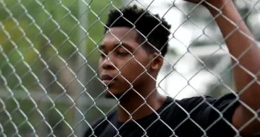 Young black African man leaning on metal fence