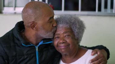 Yetişkin bir oğul, büyük anneyi öpüyor, sevgi ve ilgi gösteriyor.