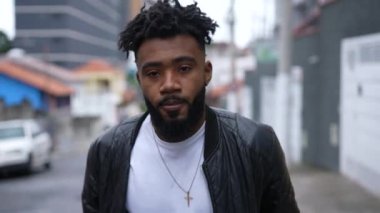 Ciddi bir ifadeyle kameraya doğru yürüyen Afro-Amerikan bir adamın portresi.