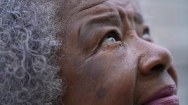 A senior African woman opening eyes to sky smiling with HOPE