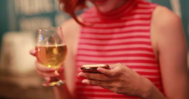 Bira içerken cep telefonunu kontrol eden kız, gerçek hayatta gül ve gülümse.