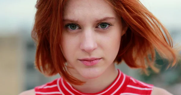 Portrait of young redhead woman staring to camera in subtle shock