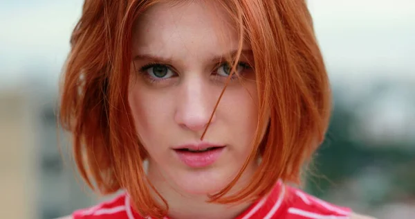 Portrait of young redhead woman staring to camera in subtle shock